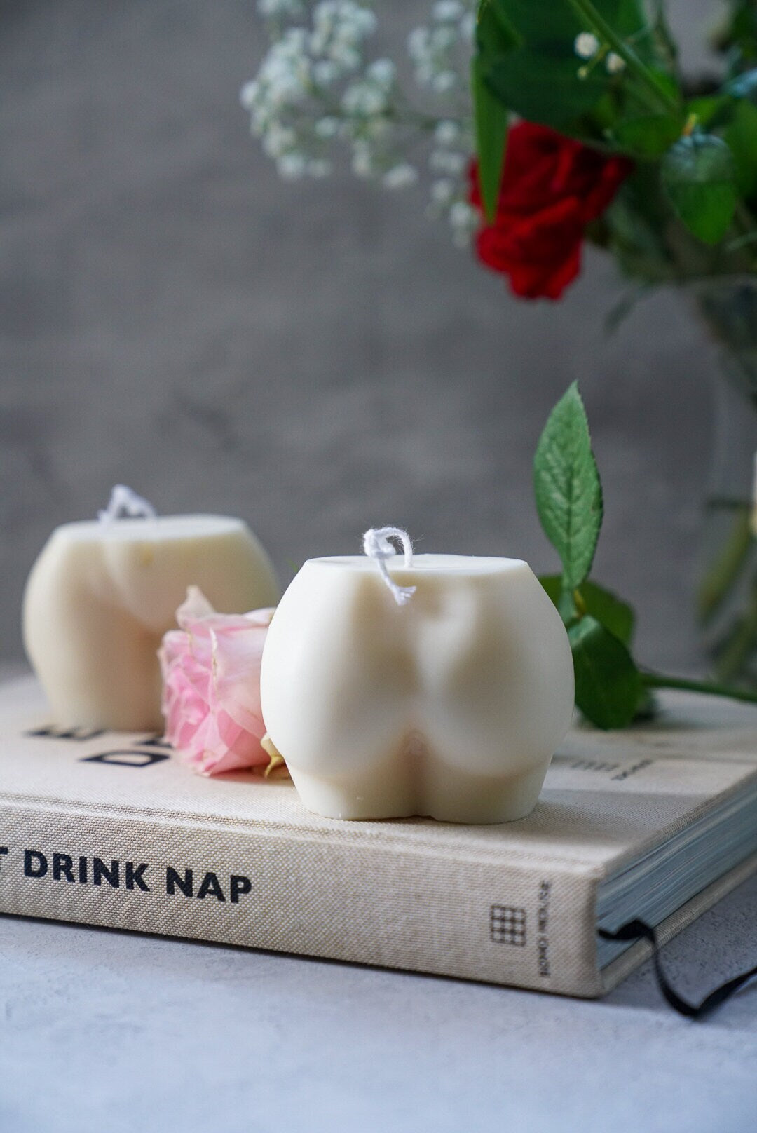 Extra Large Bottom Candles on a magazine with pink rose on the side sitting on magazine.