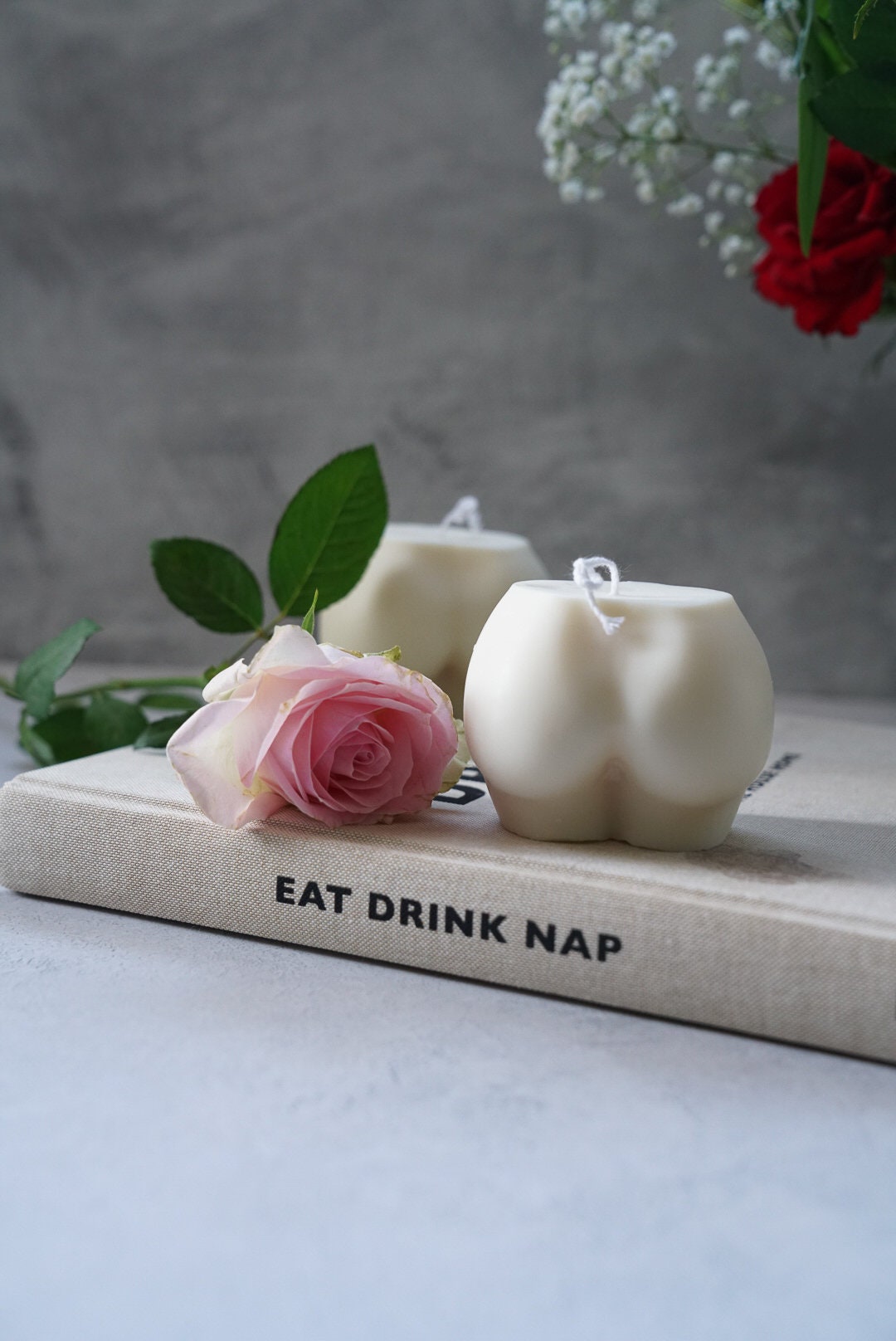 Extra Large Bottom Candles on a magazine with pink rose on the side and sitting on magazine.