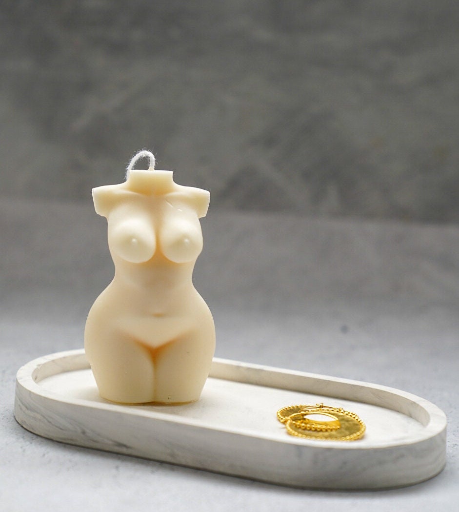 Curvy Goddess Candle in a trinket tray with gold earrings.