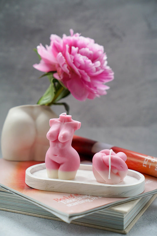 Curvy Goddess Candle with knot candle on a trinket tray with pink peony on a bottom vase on the background.