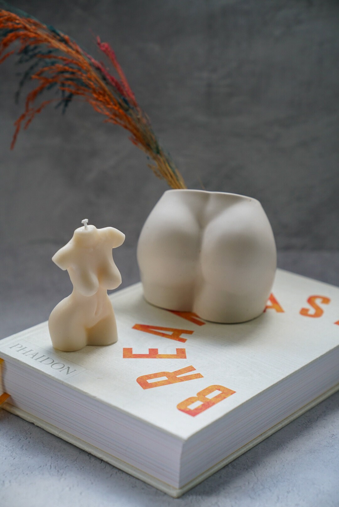 Concrete Booty Decorative Vase and naked lady body. both on the book with a grey background.