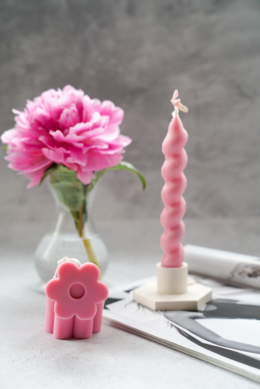 Pink Daisy Flower Arch Candle with peony on the background in a glass vase with twisted candle on a candle holder