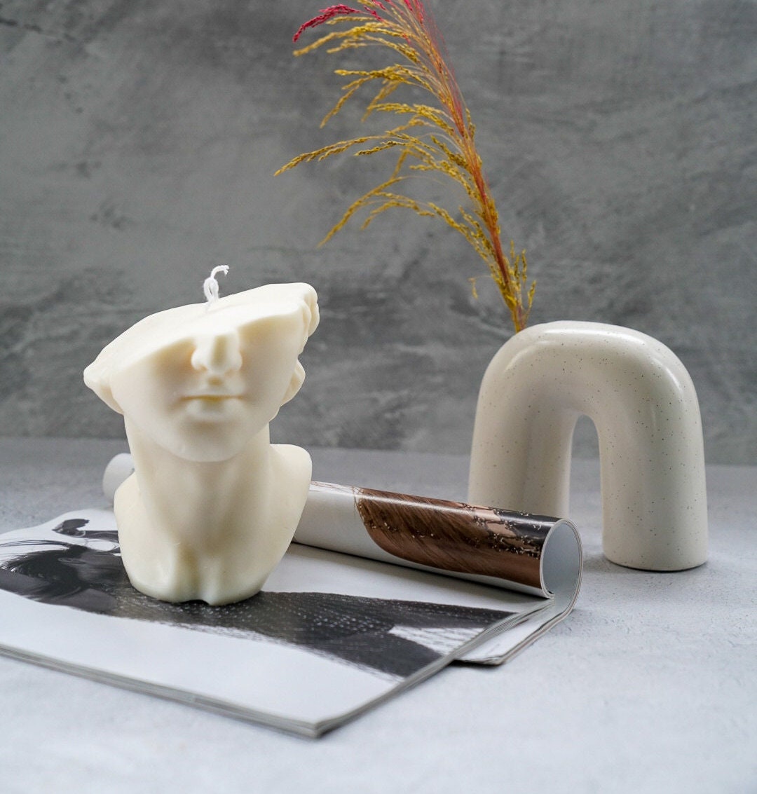 Half David Head Statue Candle and white vase on the back.