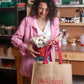 Woman holding a red bucket with flowers and a brown bag with 'gokican' branding in a workshop setting.