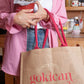 Person holding a pink tote bag with 'gokican' branding in a kitchen setting.