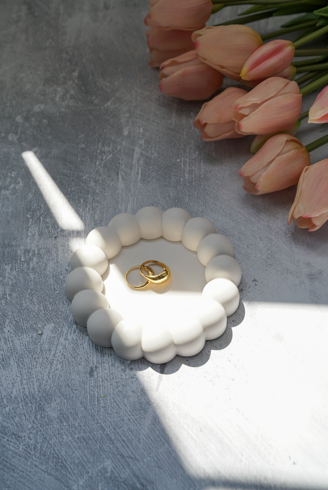 Bubble Jewellery Holder with gold rings on it Tulips on the side on a grey background 