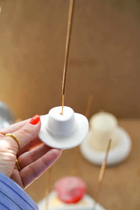 Holding Off White Cowboy Hat Incense Holders with incense in it.