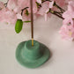 Zen Green  Cowboy Hat Incense Holder with incense in it with flowers on the background. 