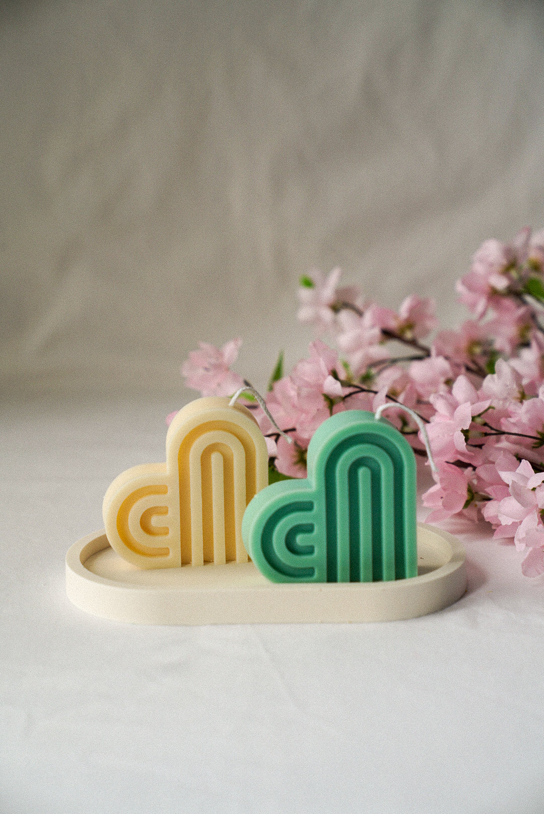 Heart-Shaped Soy Wax Candles on a trinket tray flowers on the background. 