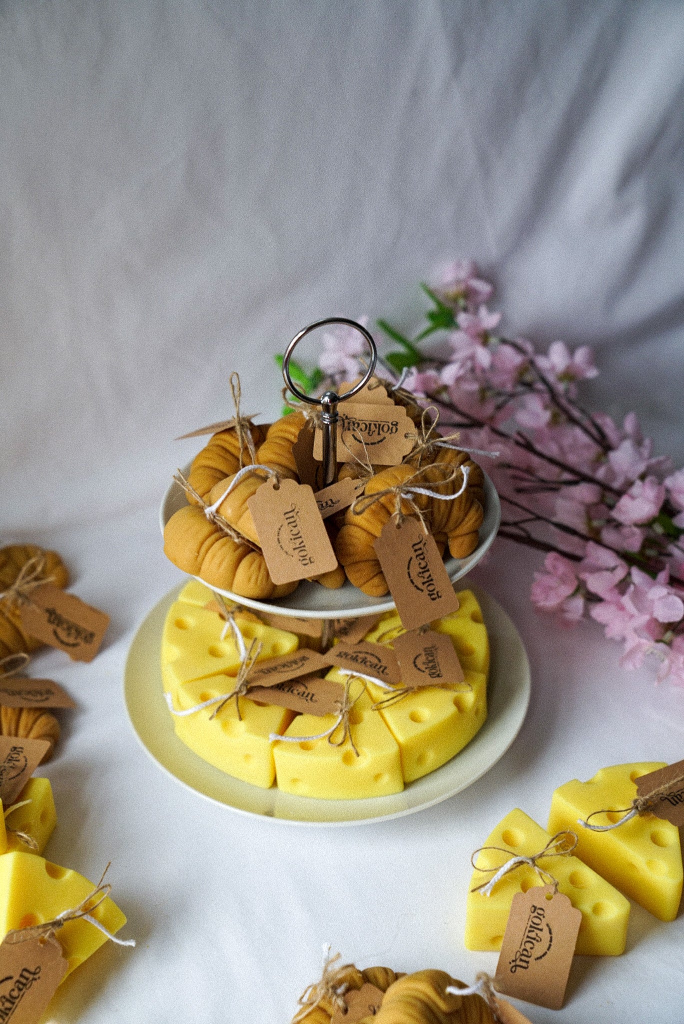 Cheese and croissant shaped candles are on the 2 floor plate with flowers on the background.