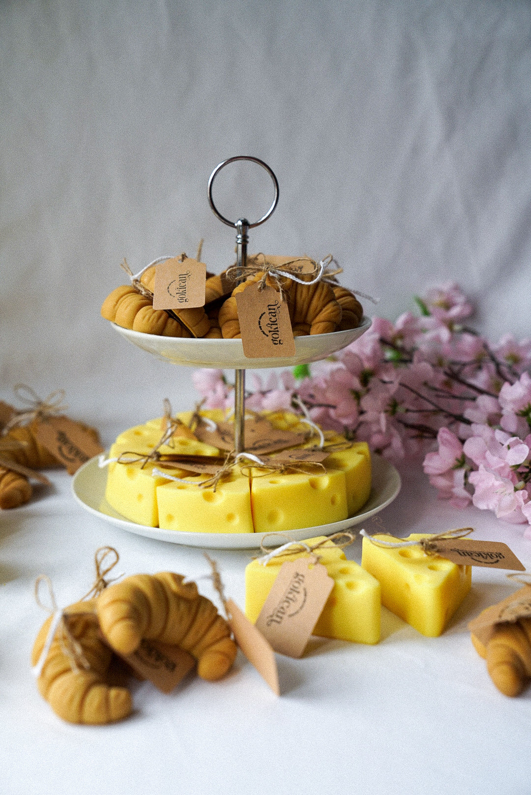 Cheese and croissant shaped candles are on the 2 floor plate with flowers on the background.