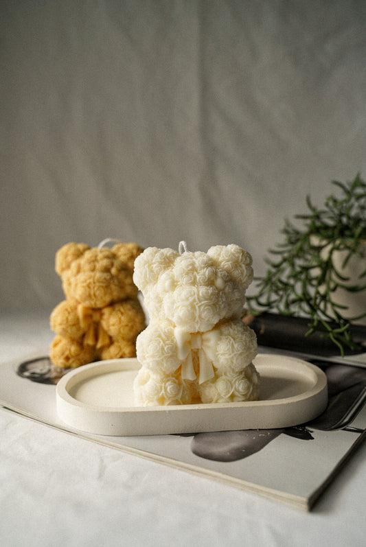 Ivory Flower detailed teddy candle with bow on sitting on a trinket tray