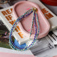 Colorful beaded necklace on a pink dish with a magazine underneath