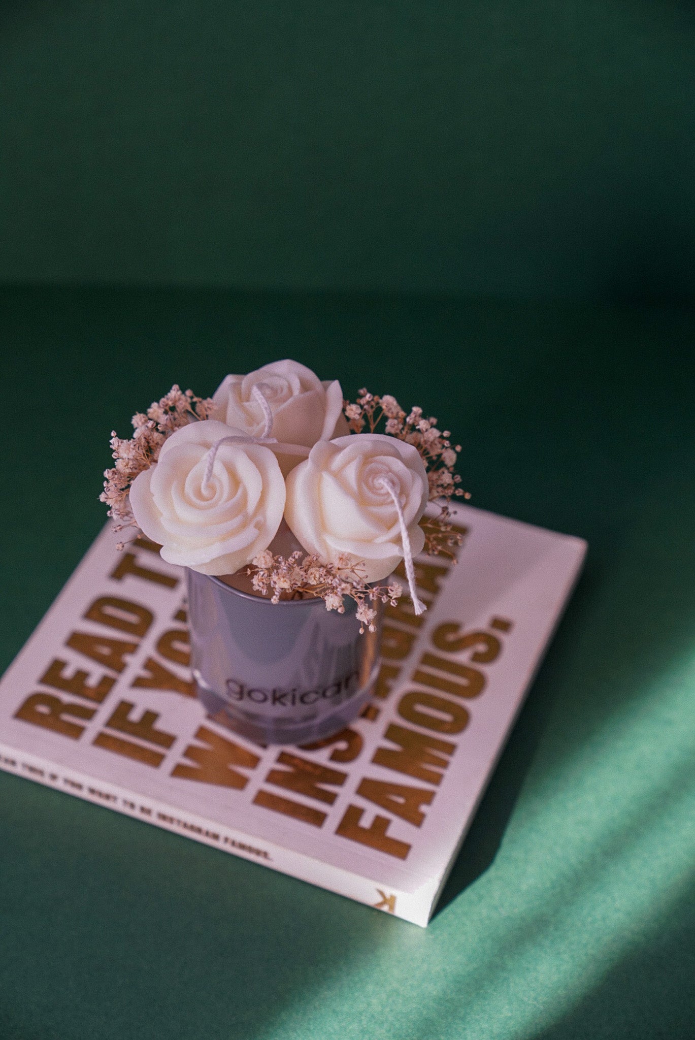 Decorative candle with flowers on a book titled 'Read to Be Famous' against a green background