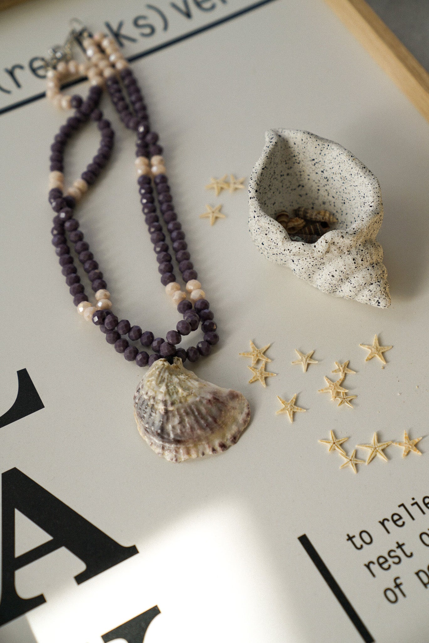 Necklace with shell pendant and decorative items on a textured surface