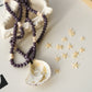 Necklace with purple beads and shell pendant on a decorative surface with star decorations