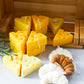 Cheese and croissant shaped soy wax candles are on the wooden box.