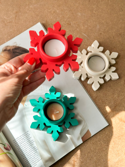 Holding Red snowflake Tea light Holder and on the background green and white snowflakes tea light holders on a magazine.