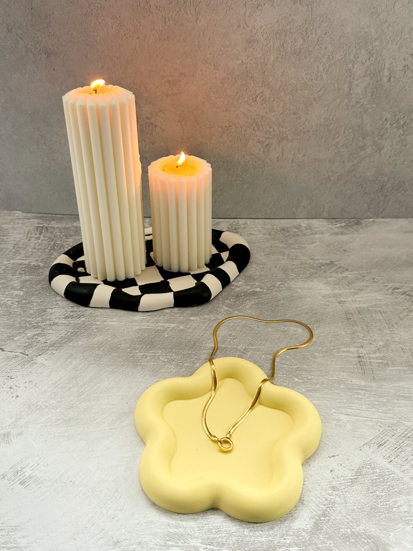 Flower Shaped Trinket Tray neckless in it pillar candles on oval trinket tray on the background. 