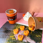 Small pumpkins in a cup on a pink surface with a blurred background