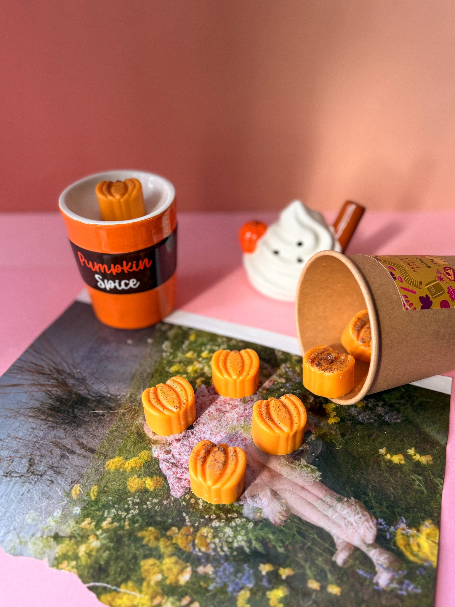 Small pumpkins in a cup on a pink surface with a blurred background