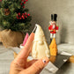 Holding Gnome Scented Candles with nutcracker and Christmas tree on the back.
