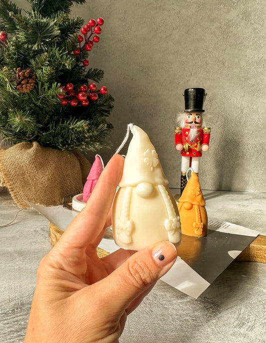 Holding Gnome Scented Candles with nutcracker and Christmas tree on the back.