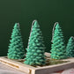 Green Christmas tree-shaped candles on a book with a green background