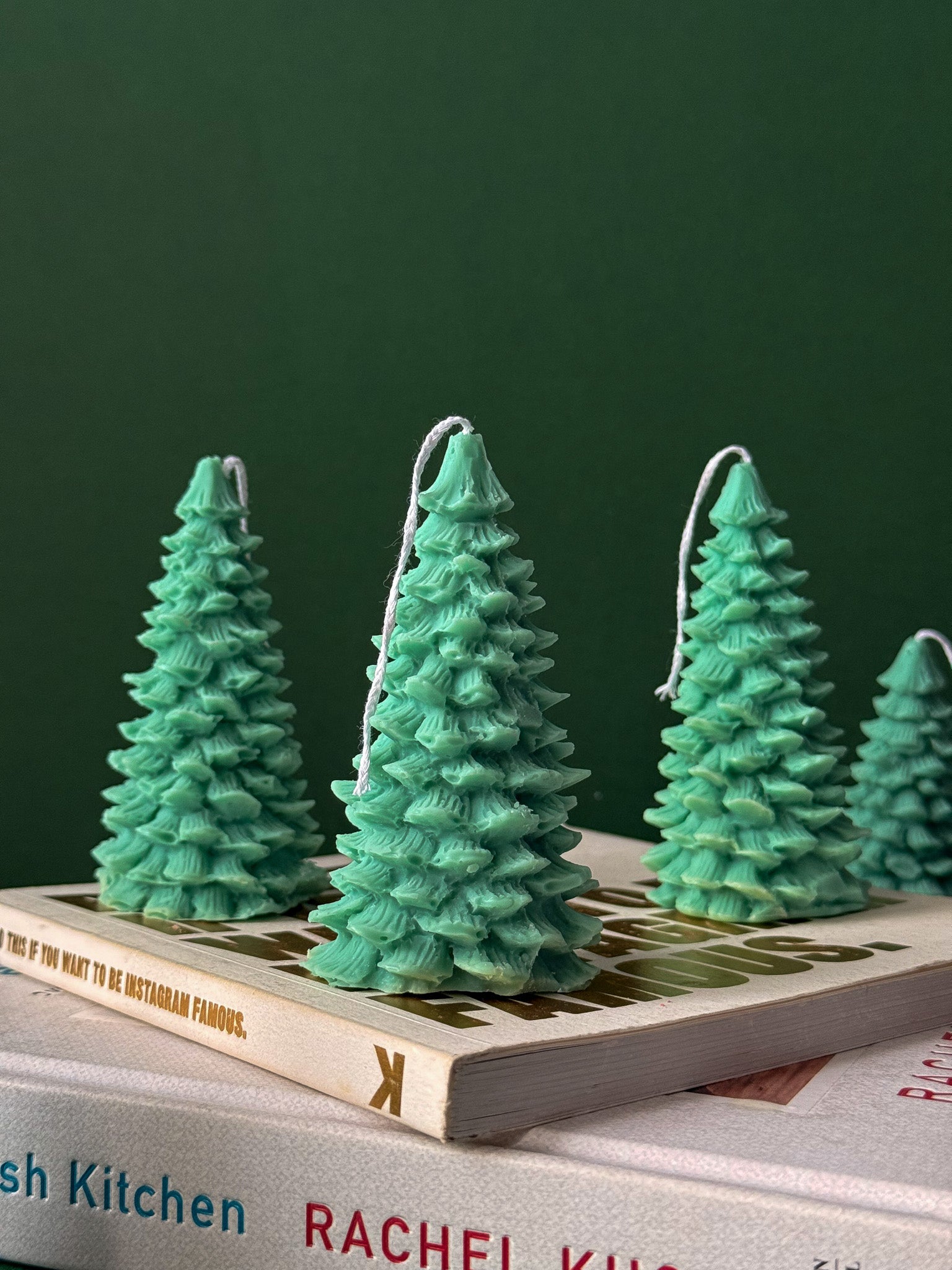 Green Christmas tree-shaped candles on a book with a green background