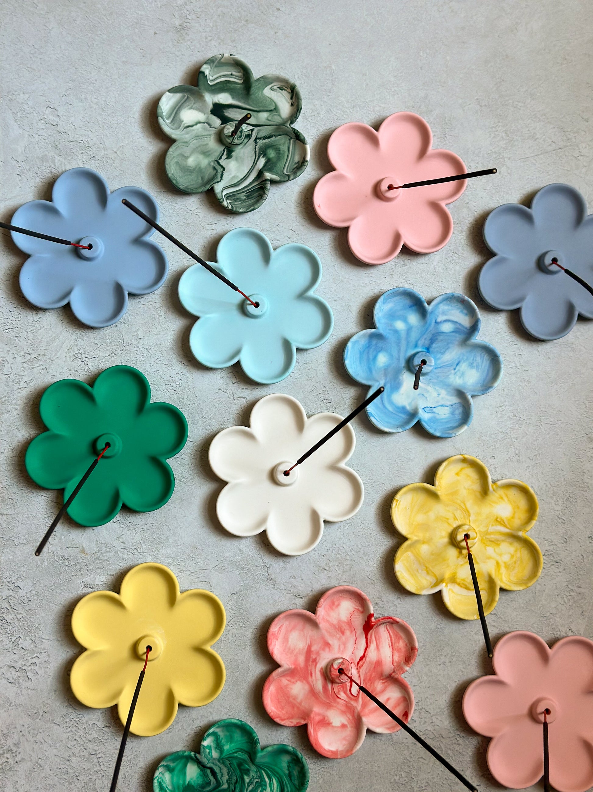 Colourful Flower Shaped Incense Holders with sticks on them.