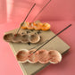 Incense stick holders on a wooden tray with a pink background