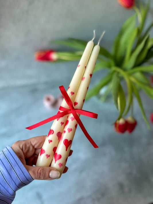 Holding Heart Hand-Painted Pillar Candles with ribbon on it.