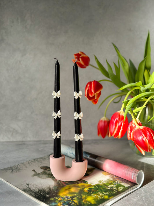 Black candle with 3D bow candle with the pink U shape candle holder is on the magazine Tulips on the background