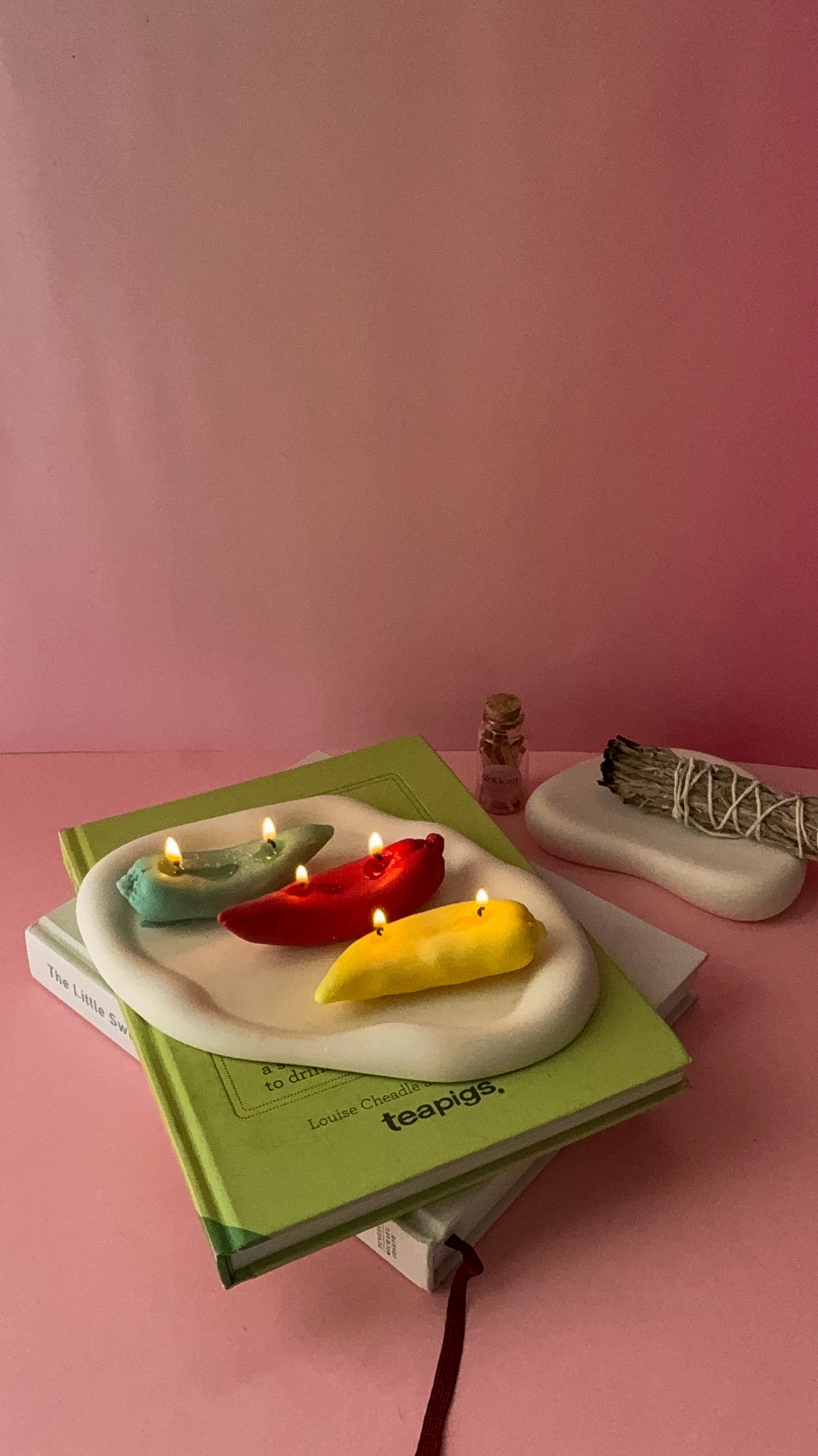 Burning Chile Pepper Candles are red green and yellow sitting on the plate with pink background