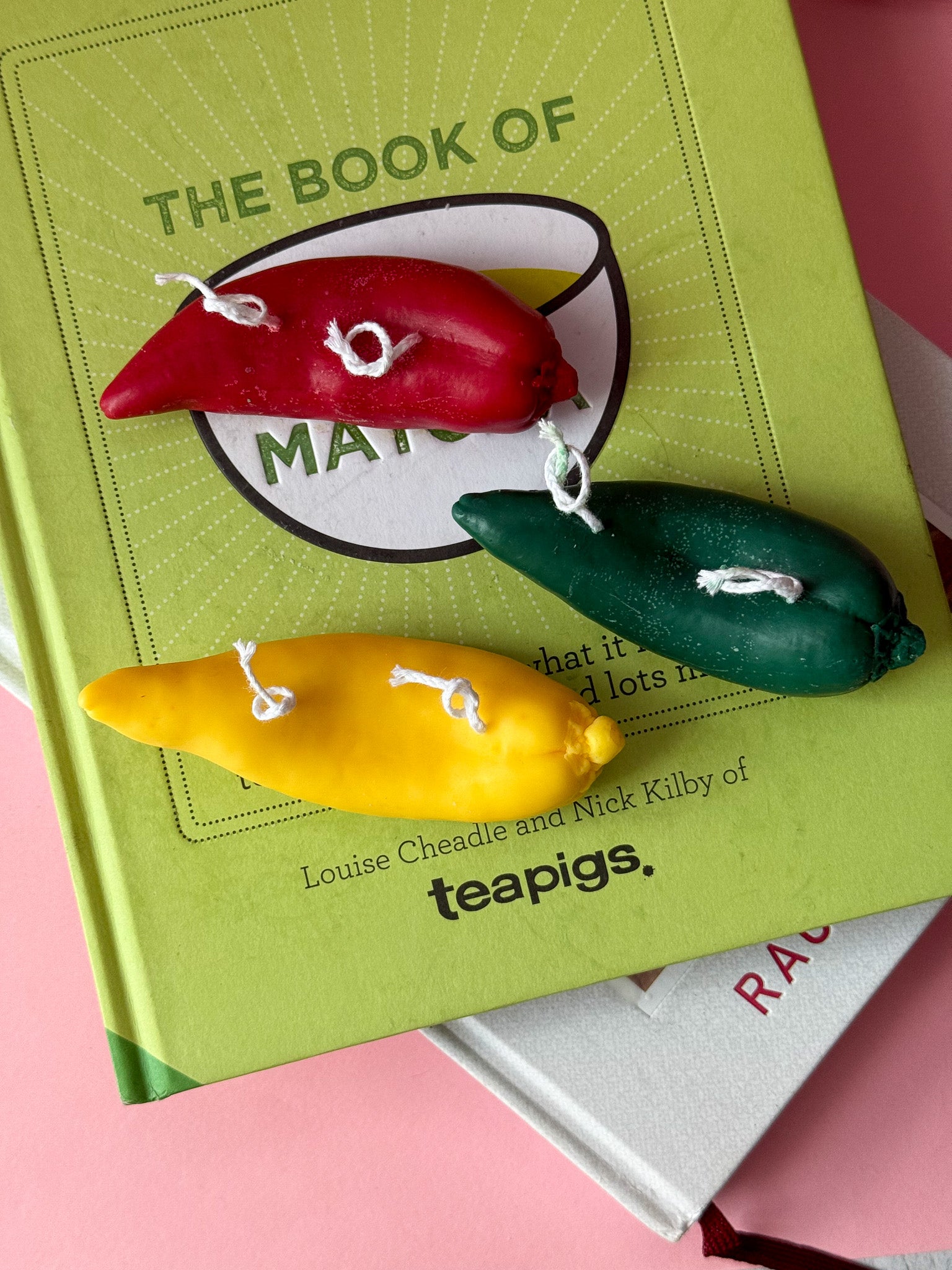 Green book titled 'The Book of Matcha' with colourful matchbook charms on a pink background