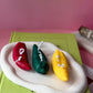 Three colourful chilie pappers on a white base with a pink background