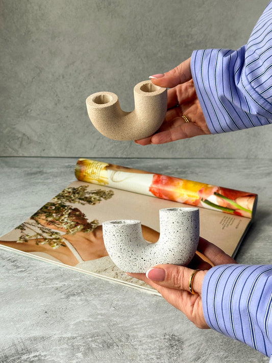 Holding Earthy U Shape Dinner Candle Holder Stone Textured with magazine on the background. 