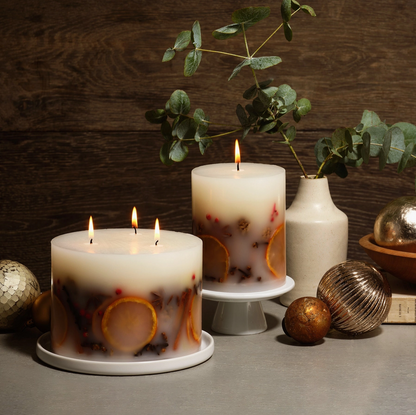 Two lit candles with decorative elements on a wooden surface