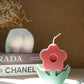 Flower Pillar Candle on a trinket dish with bottom vase and magazine on the background
