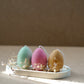 3 different colour Easter Egg  Candles on a trinket dish with dry flowers around. 