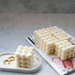 Ivory bubble candle with jewellery tray on a magazine with grey background