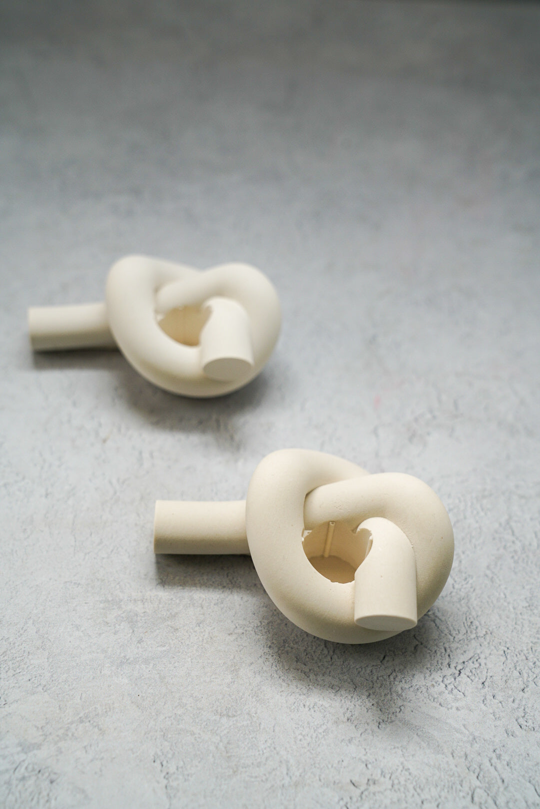 Knot Shaped Candle Holders in a grey background. 