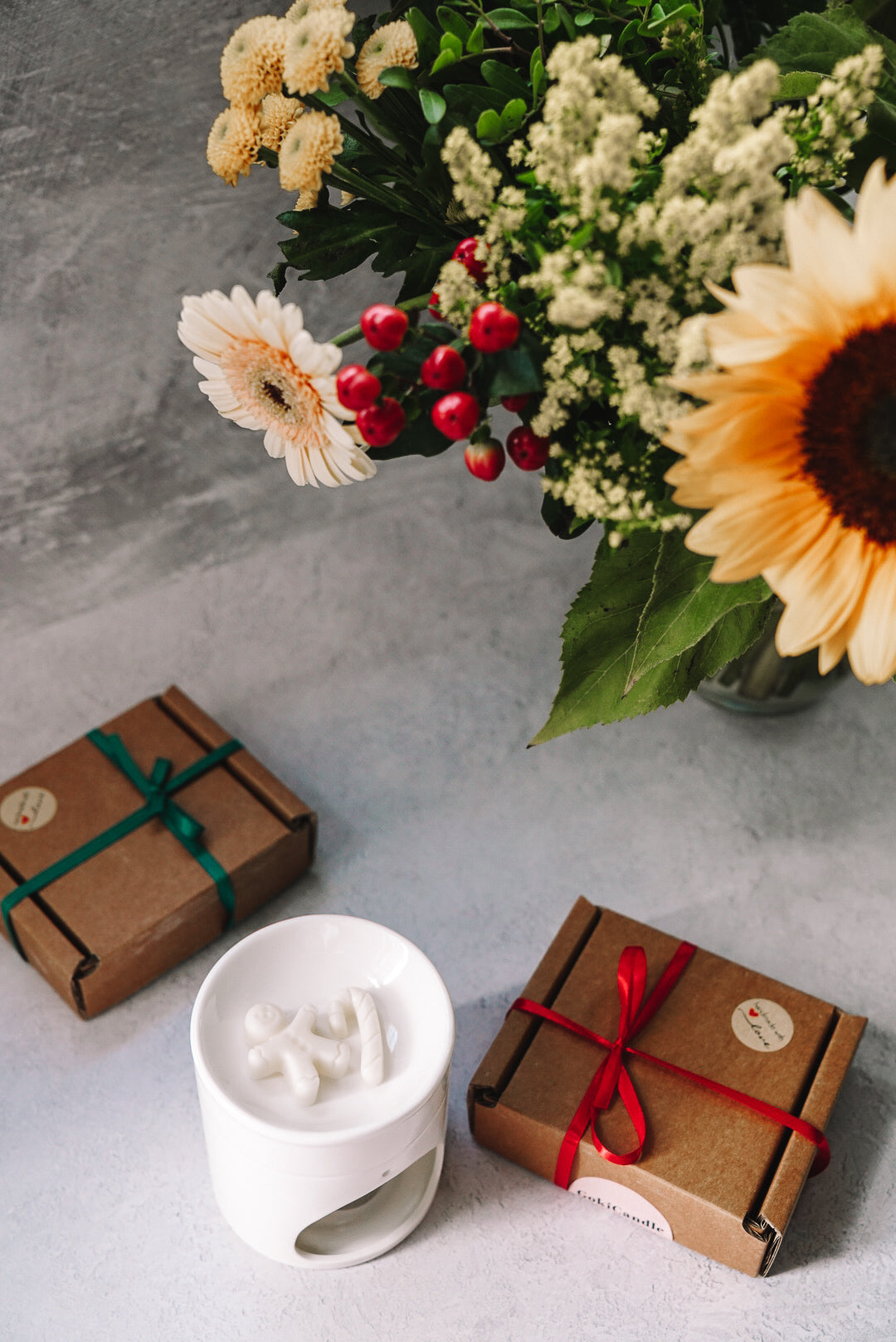 Christmas Spice Scented Gingerbread Wax Melts in a wax melter with gift boxes and flowers on the background.