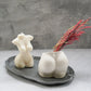 Concrete Booty Decorative Vase with dry flowers on it . Female torso soy wax candle sitting on a trinket tray