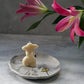 Large Round Jewellery Dish with torso candle on it, flowers on the background.