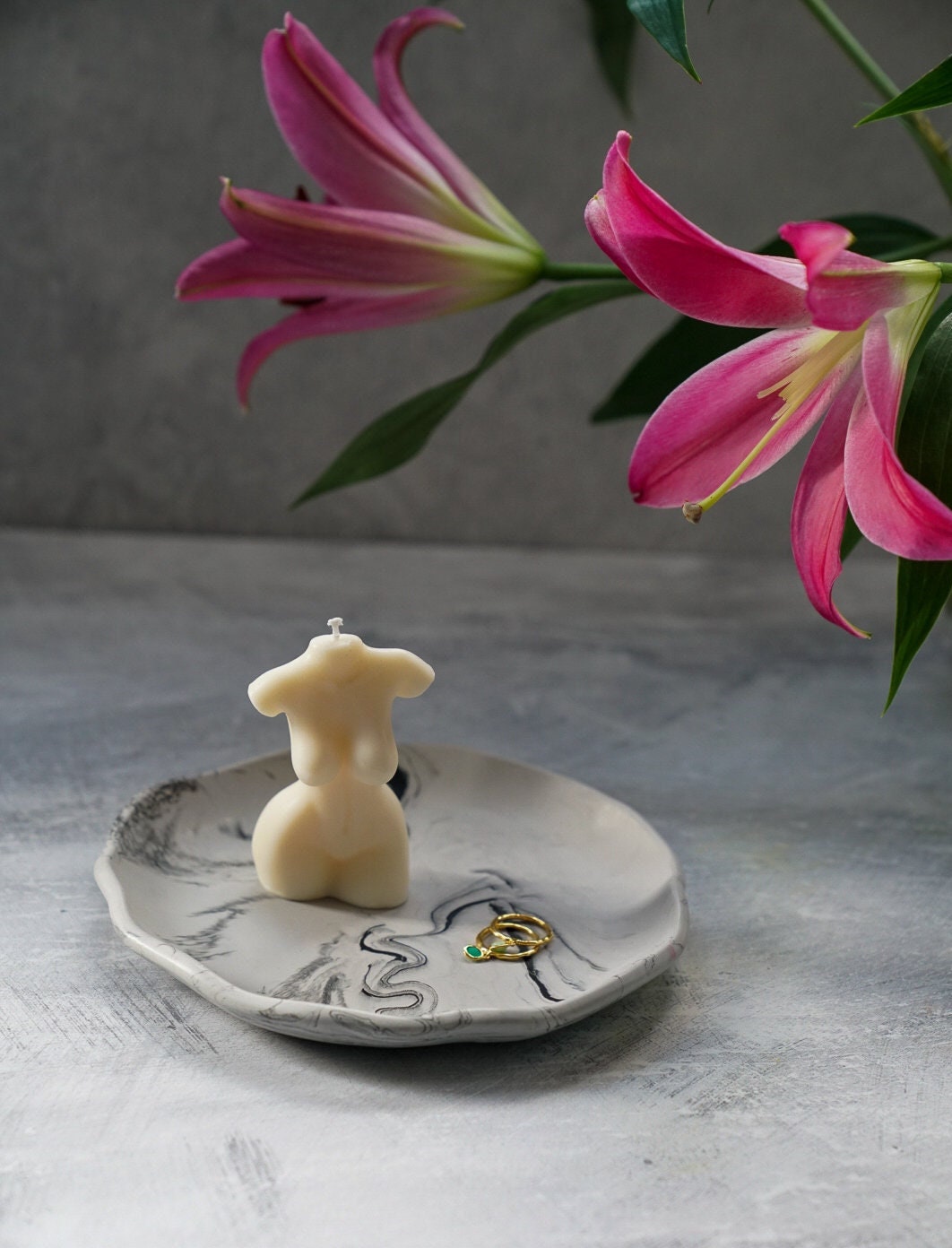 Large Round Jewellery Dish with torso candle on it, flowers on the background.