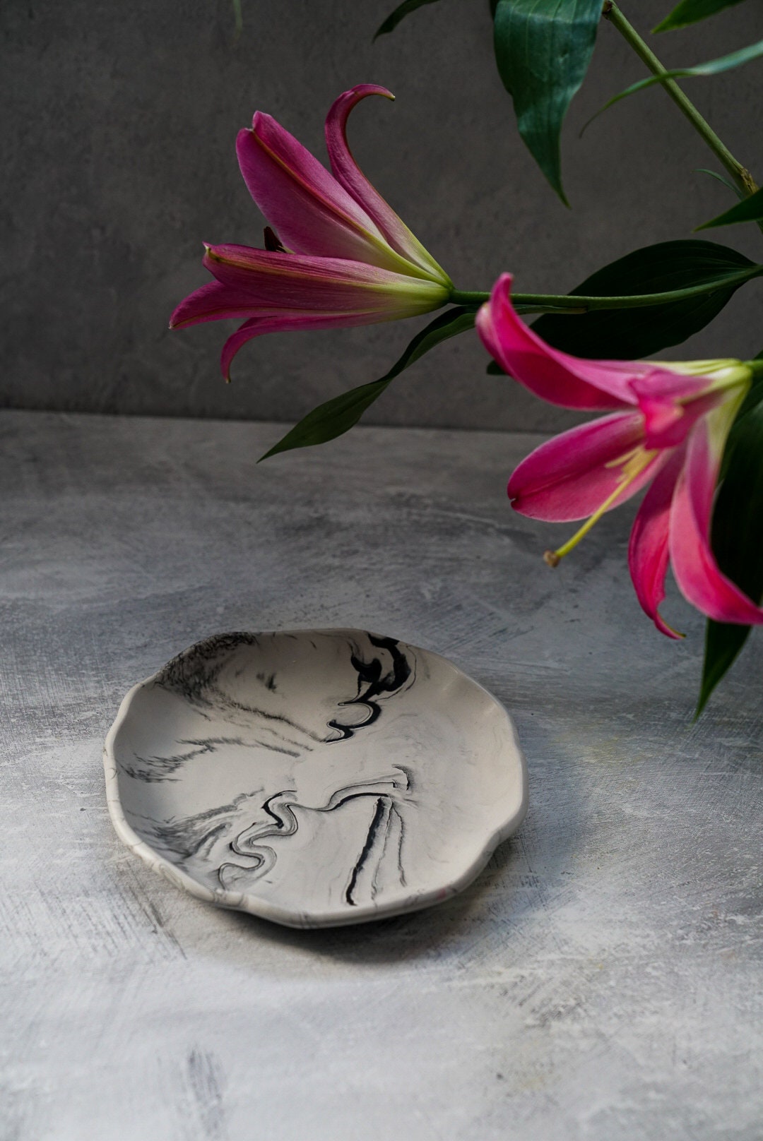 Large Round Jewellery Dish with XL bubble candle on it, flowers on the background.