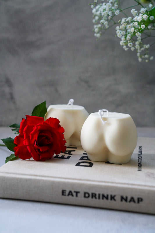 Extra Large Bottom Candles on a magazine with red rose on the side sitting on magazine.