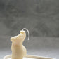 Curvy Goddess Candle from the side on a trinket tray with gold earrings on it.
